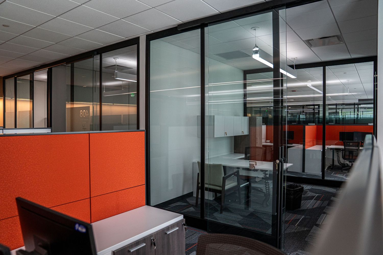Modern office interior with glass partitions and orange accent walls under construction.