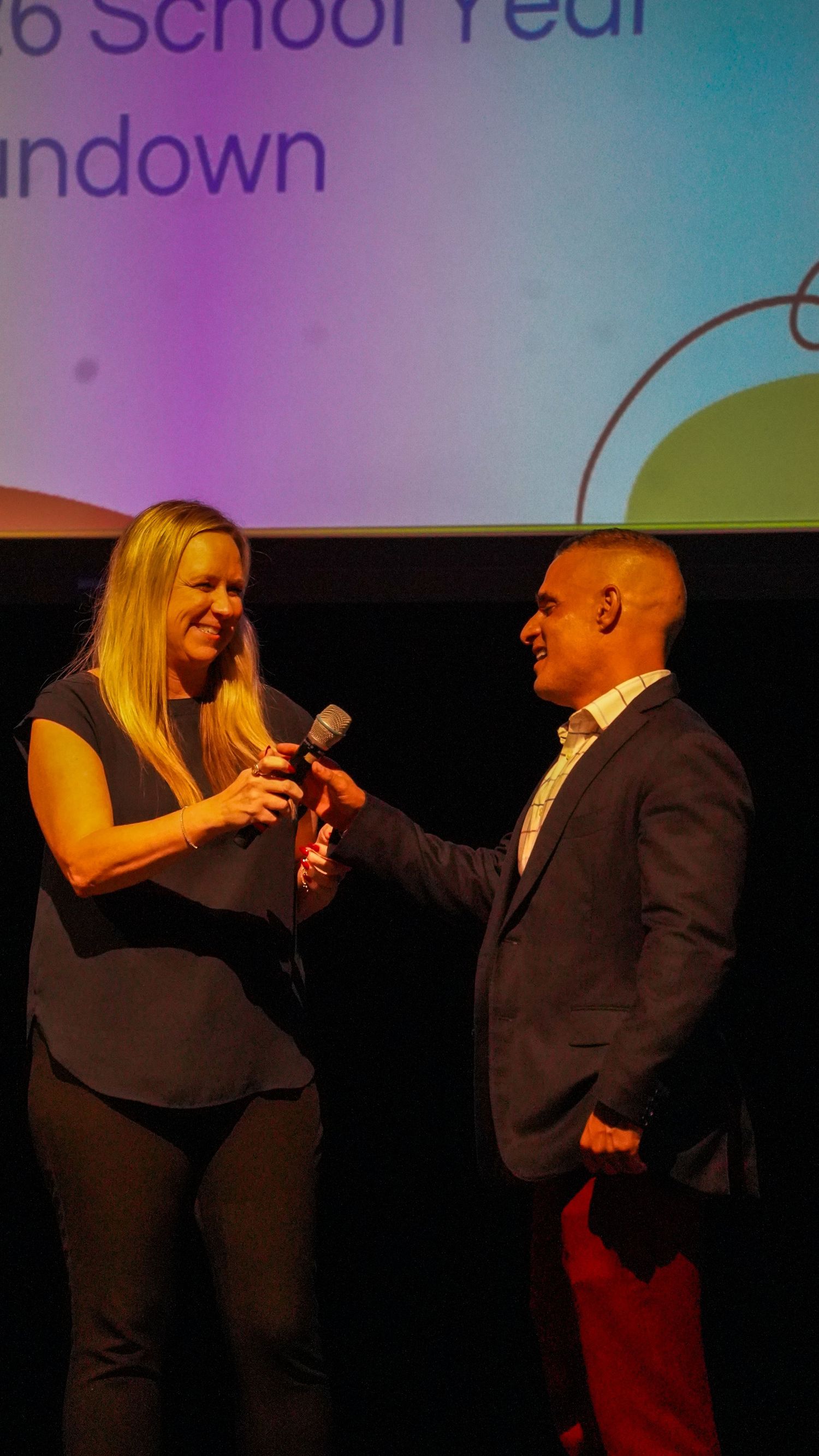 Two performers sharing a moment on stage during a school presentation.
