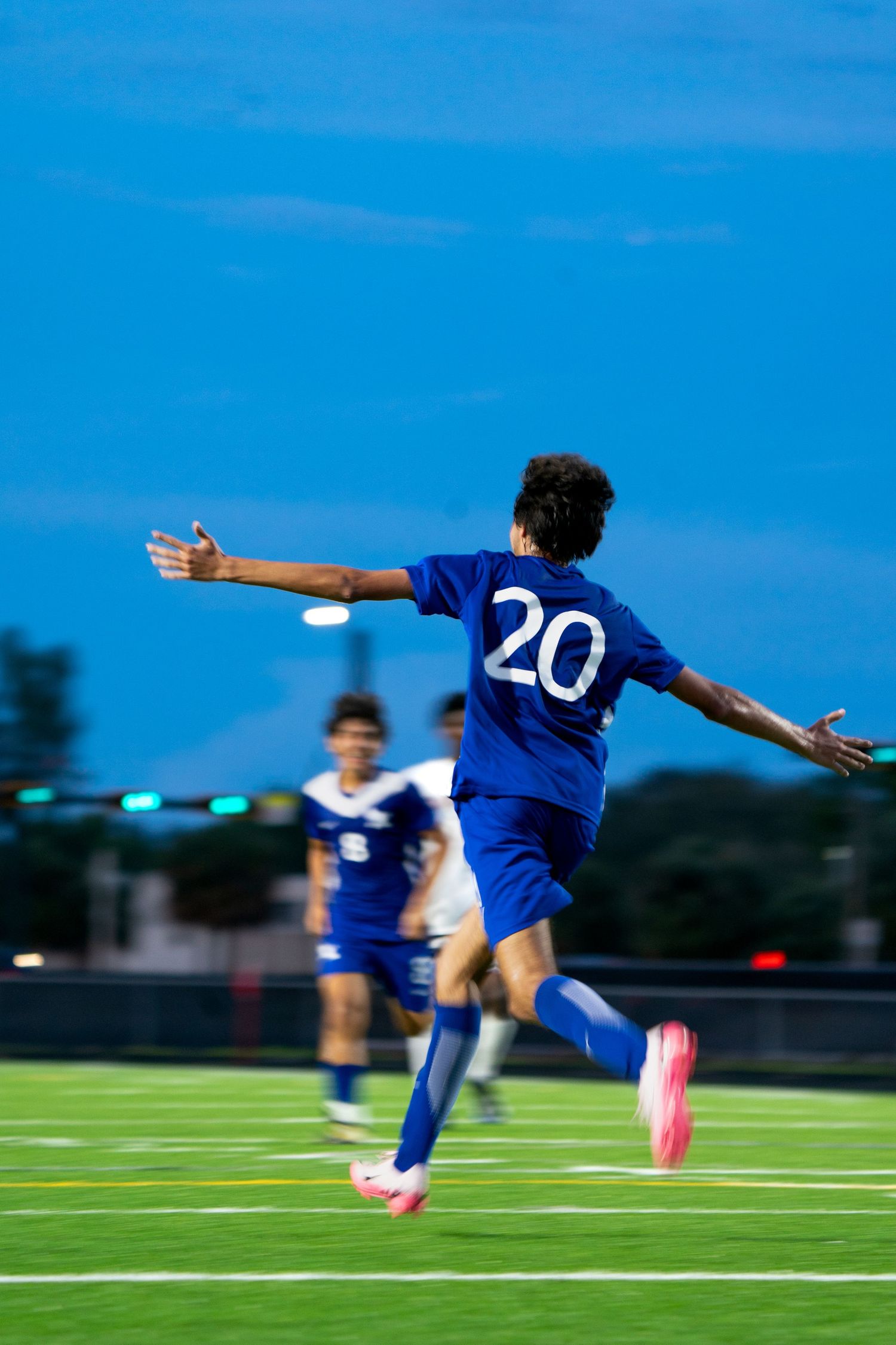 Soccer player in blue uniform executing an acrobatic kick on the field.