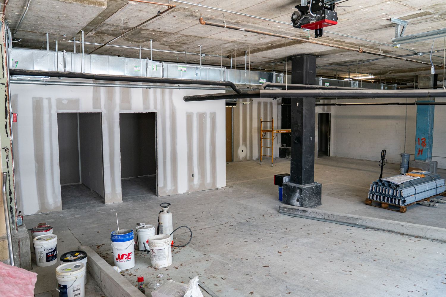 Construction site showing open floor plan with building materials and exposed infrastructure.
