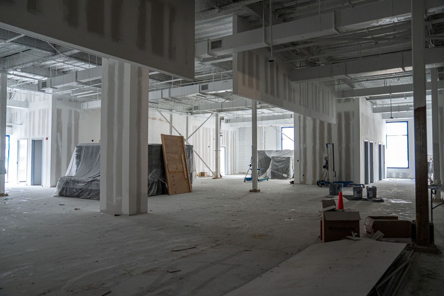Panoramic view of empty commercial space under renovation with exposed infrastructure.