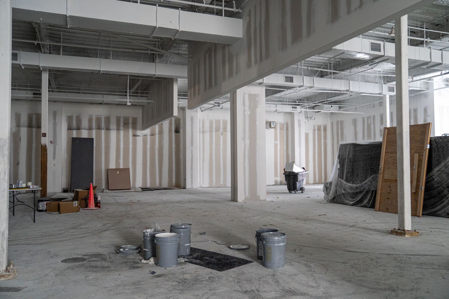 Wide angle view of industrial warehouse interior with support columns and unfinished flooring.