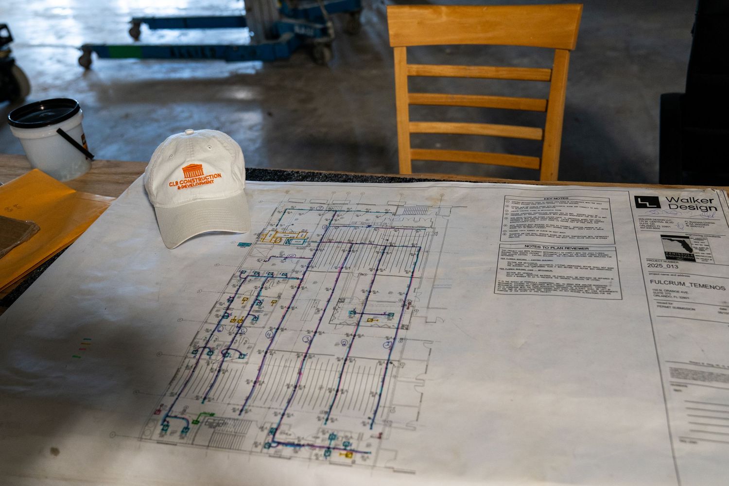 Construction blueprints and plans laid out on wooden table for review.