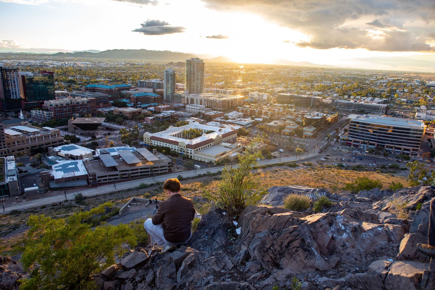 Panoramic cityscape view at sunset with mountains in background.