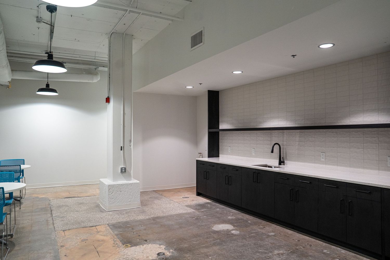Commercial office space under construction showing concrete floors and exposed ceiling infrastructure.