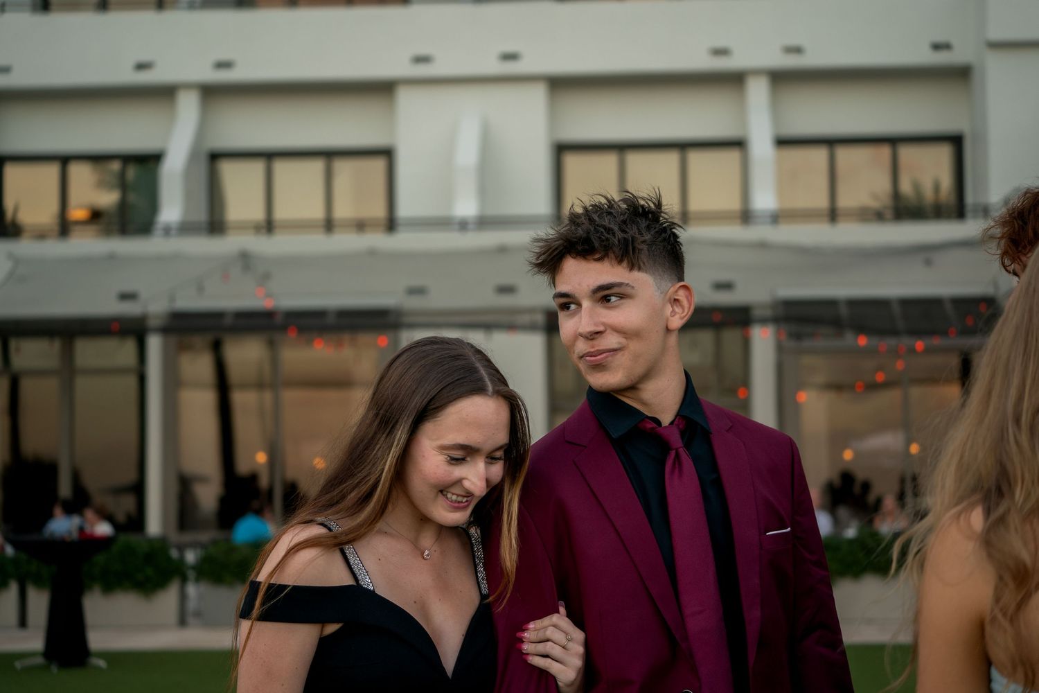 Formal event attendees in burgundy and dark attire posing outdoors.