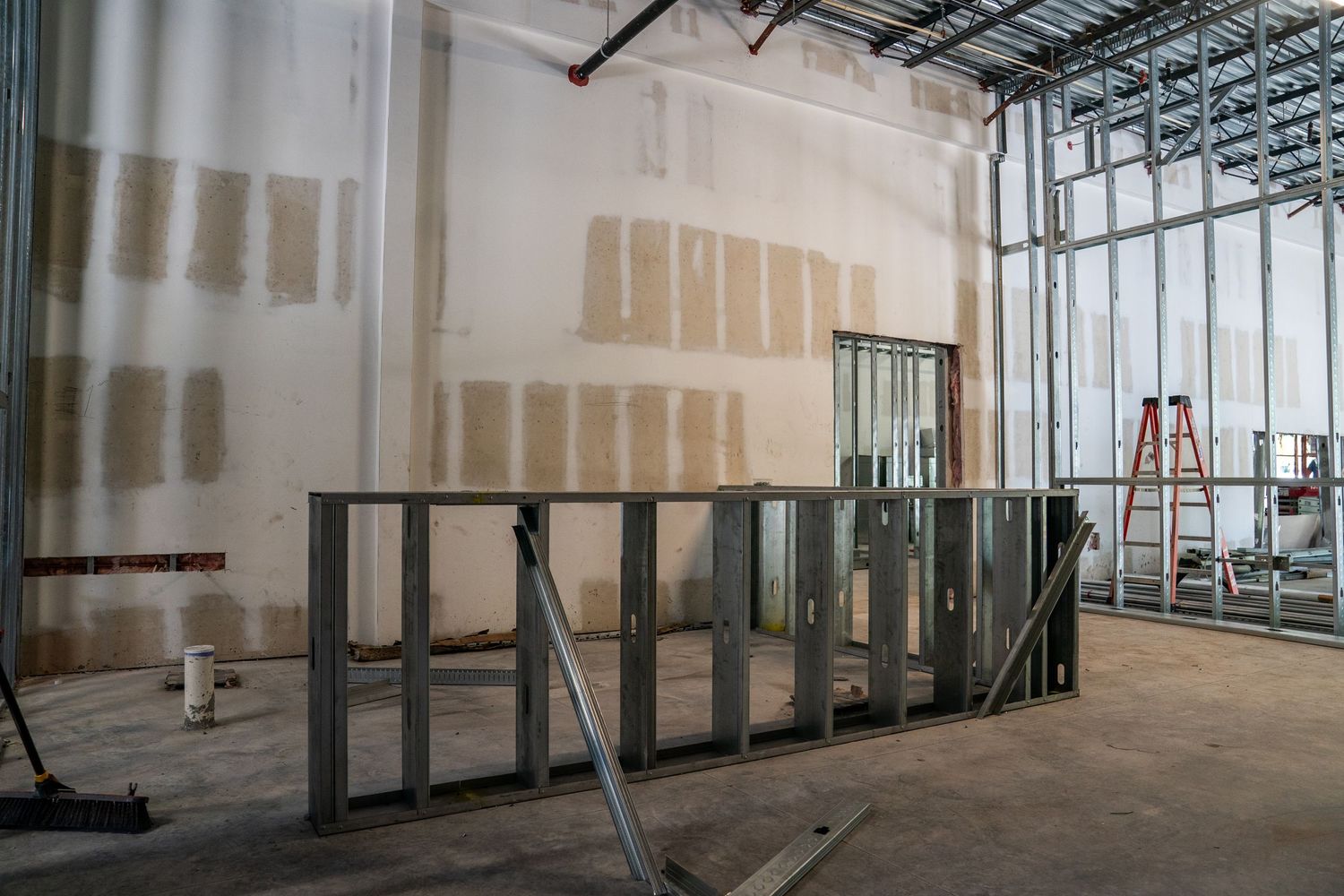 Commercial space under construction with metal studs framing and unfinished drywall walls.