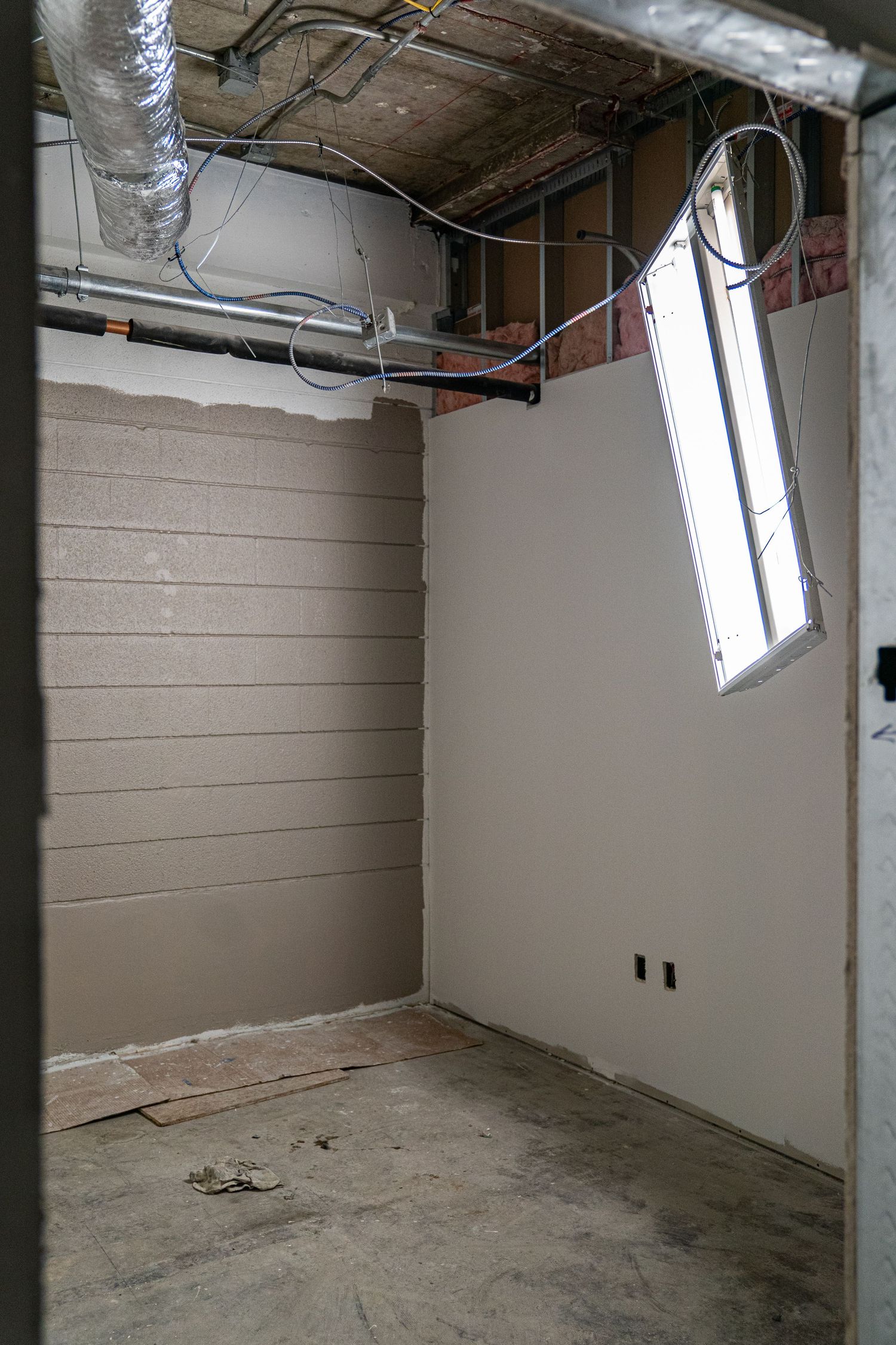 Small room with exposed utilities and windows during construction phase.