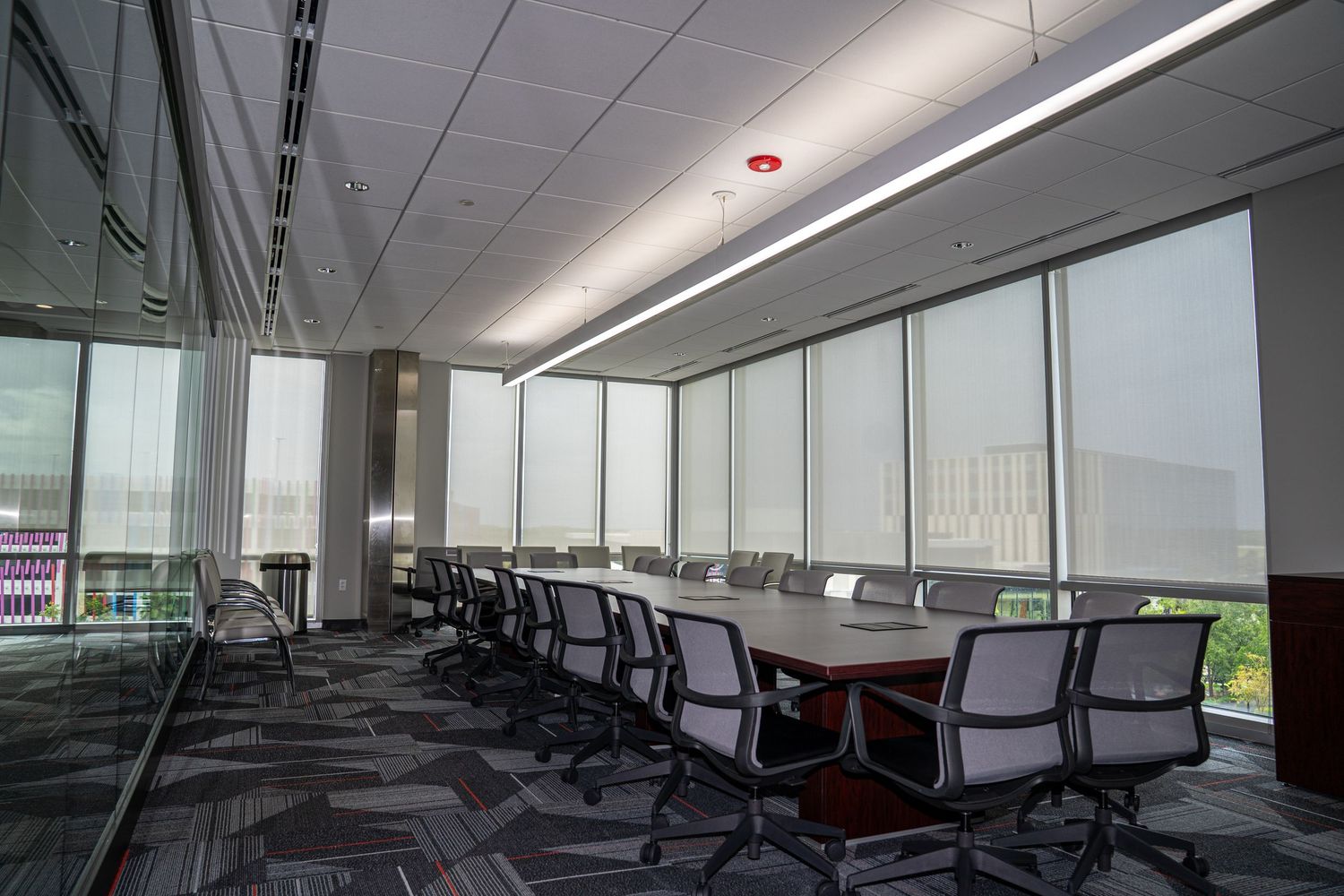 Modern office space with suspended ceiling, fluorescent lighting and large windows.