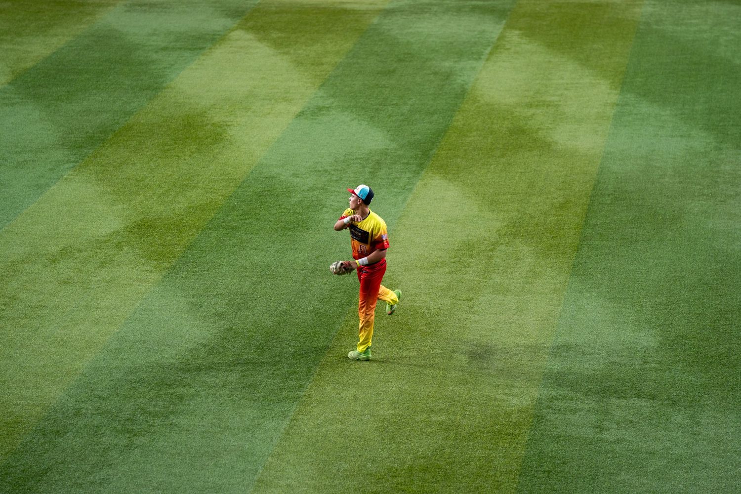 Soccer player in yellow uniform runs across bright green grass field during match action.