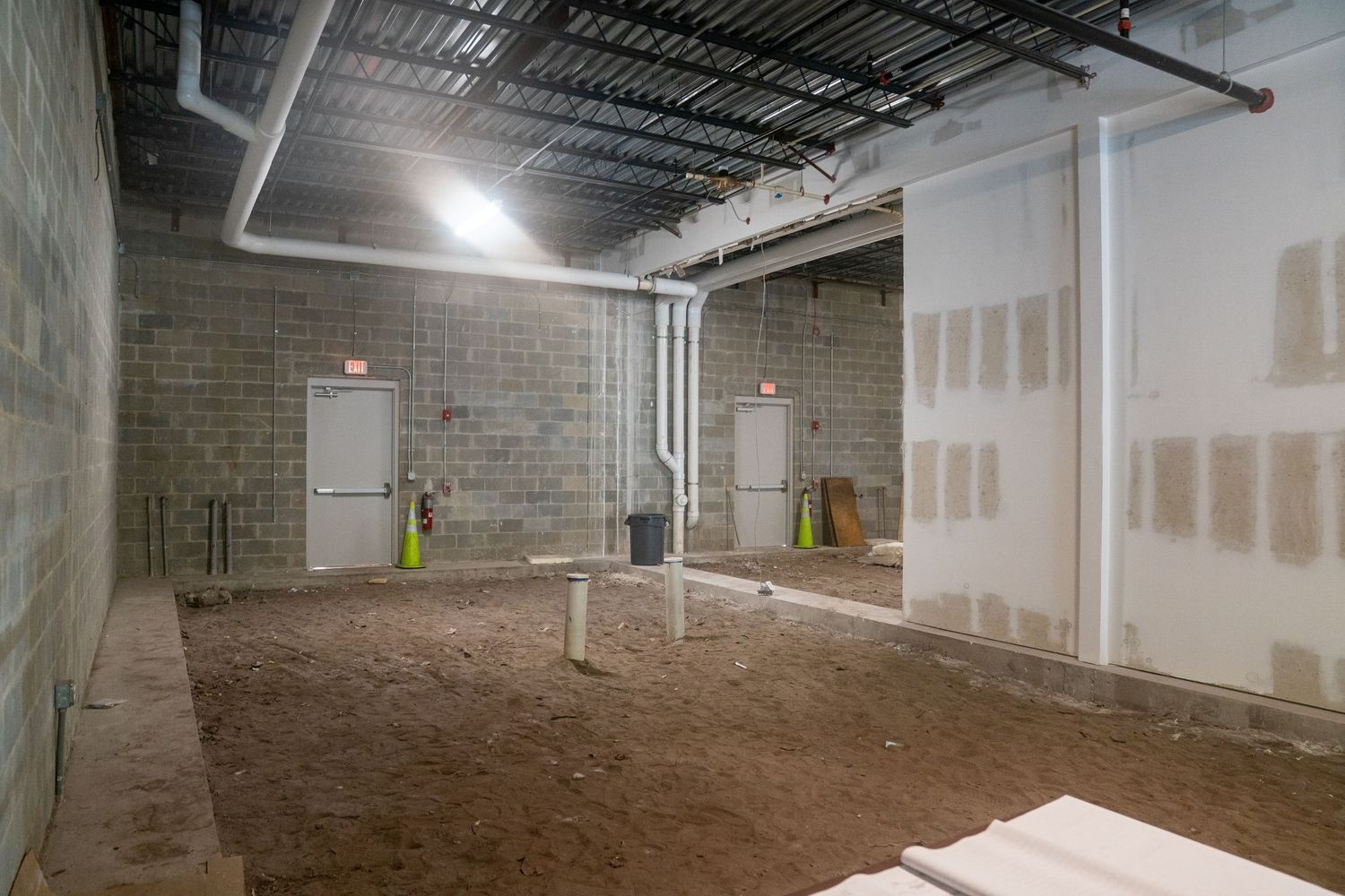Commercial space under construction showing exposed brick walls and drywall installation.