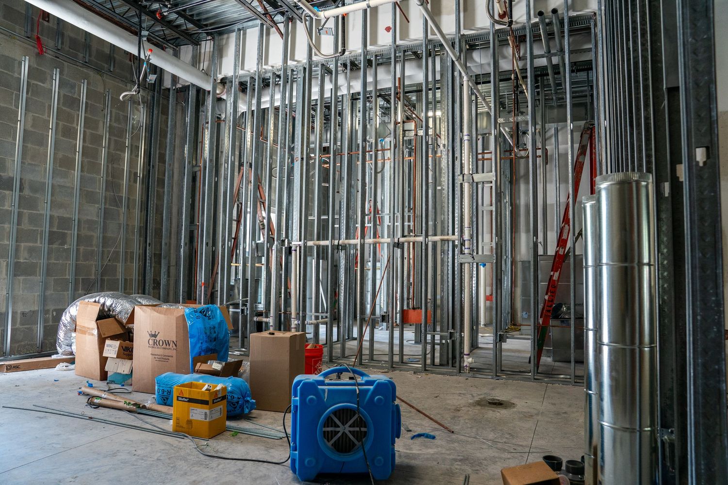 Long corridor view of commercial construction with metal framing and utility installations.
