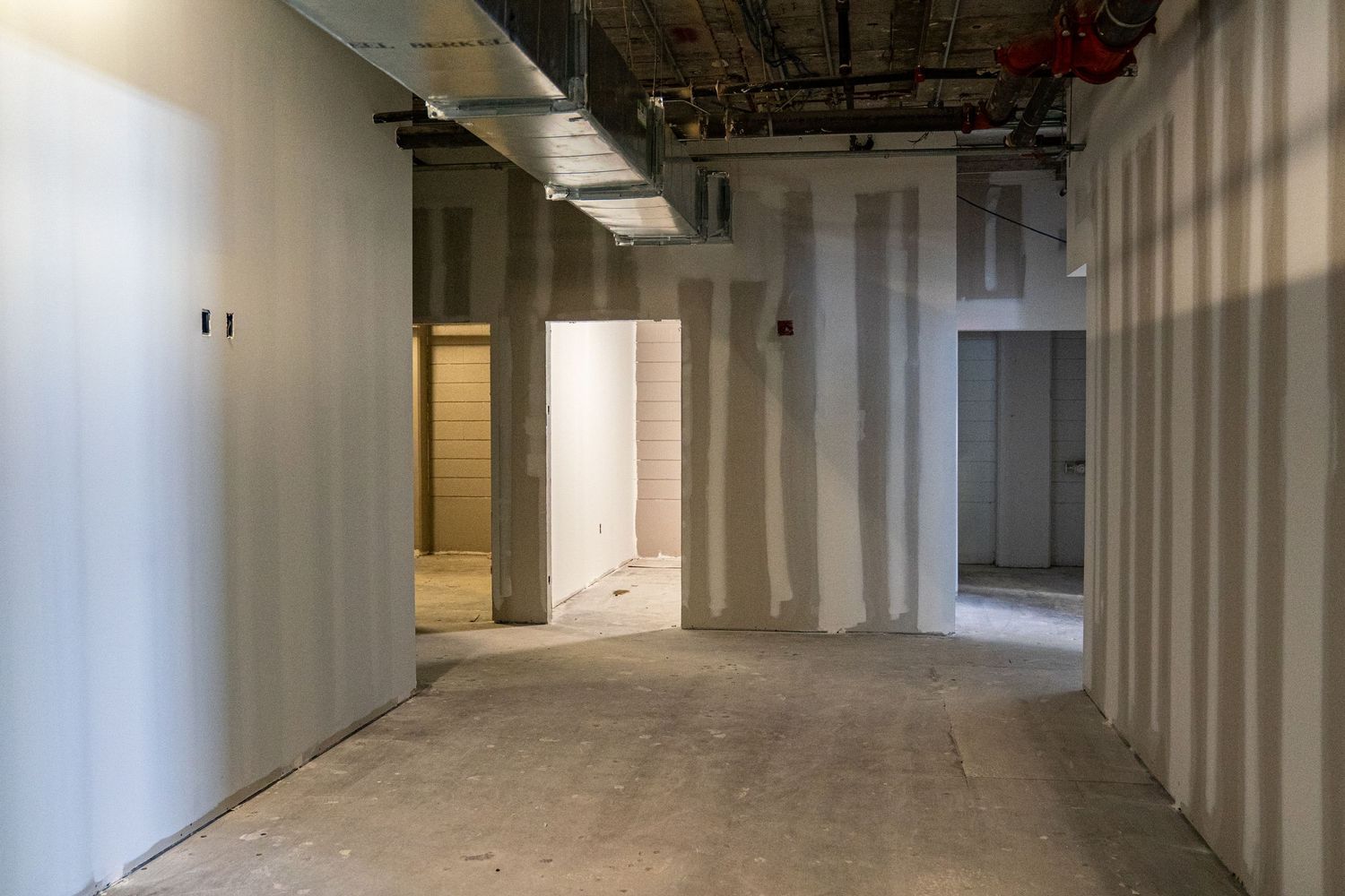 Long corridor in commercial building showing newly installed drywall and construction progress.