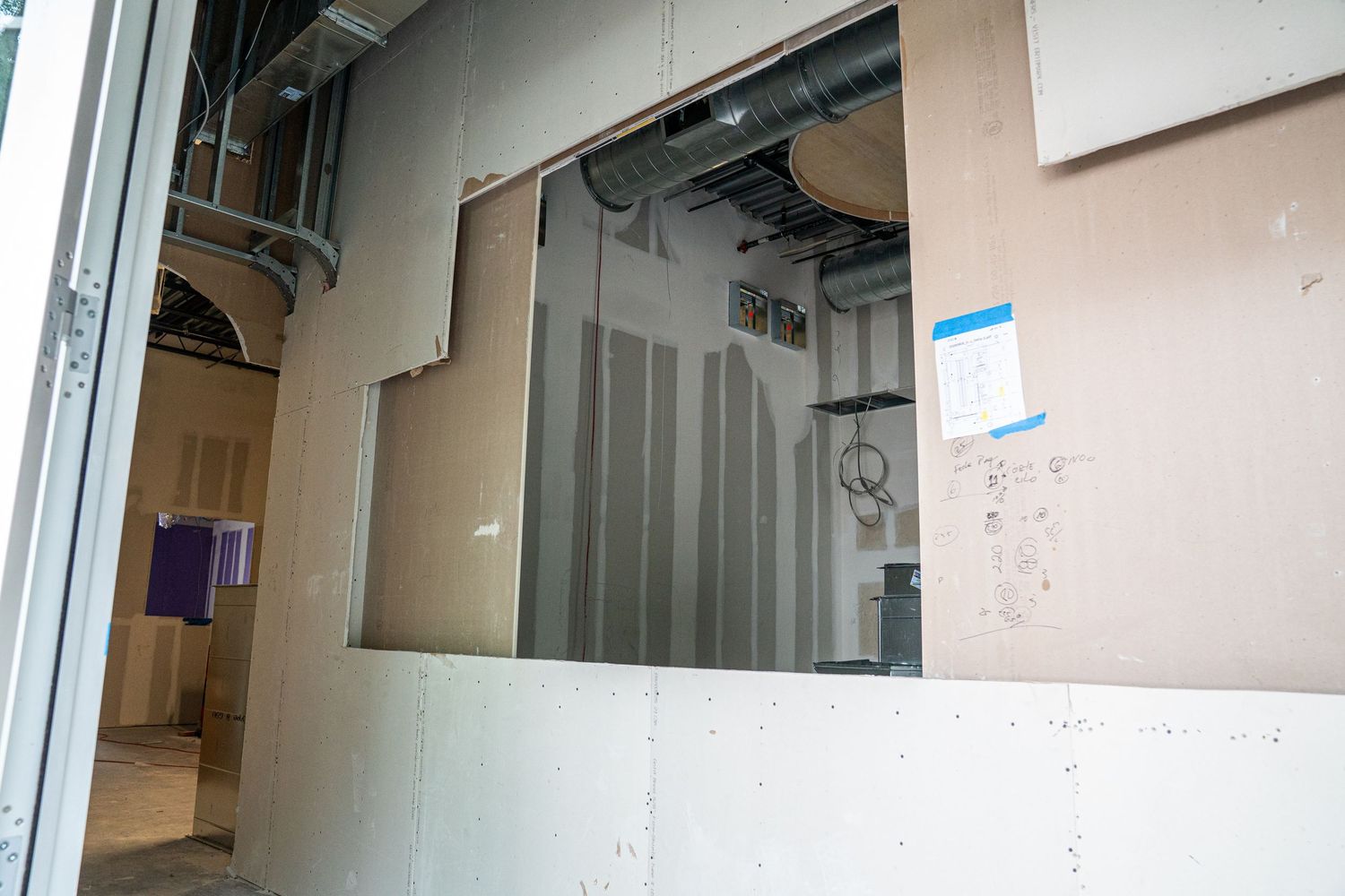 Interior view of unfinished commercial space with exposed mechanical systems and ladders.