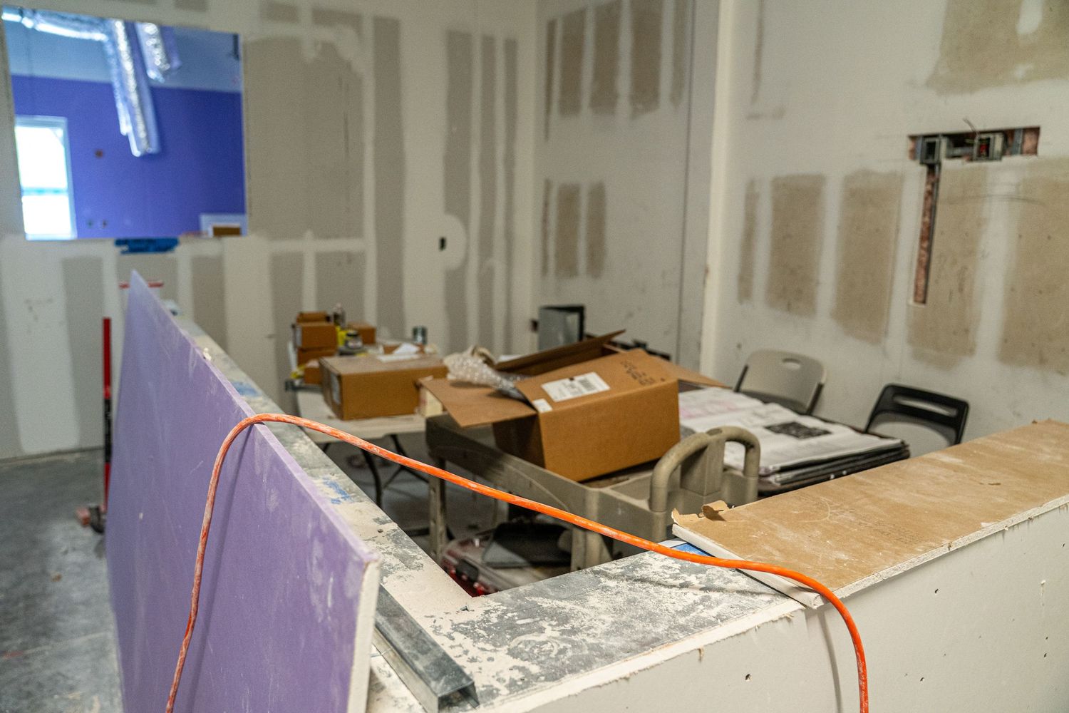 Modern office space under construction with exposed ceiling and drywall installation in progress.
