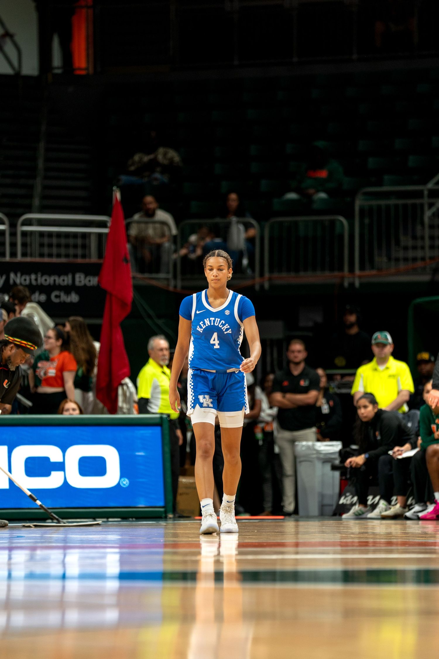 Players in blue and white uniforms stand on basketball court during game.