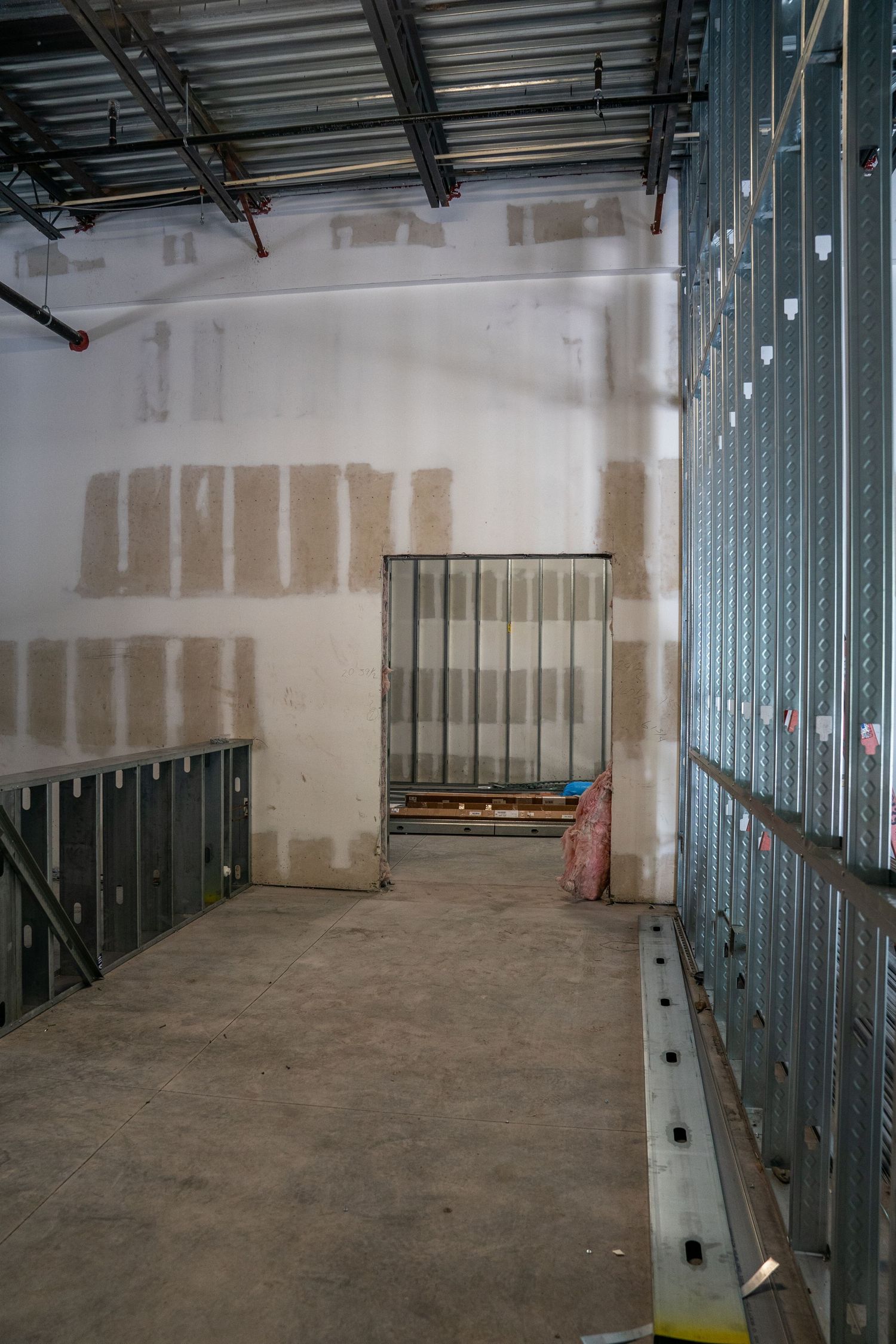 Commercial space under construction with metal framing and concrete floor visible.