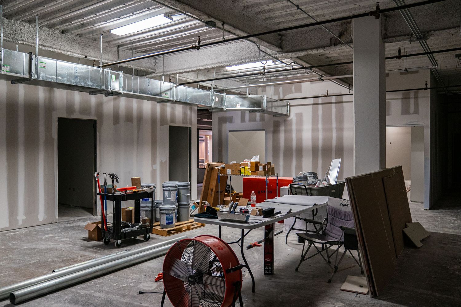 Industrial space renovation showing construction equipment and building materials scattered throughout.