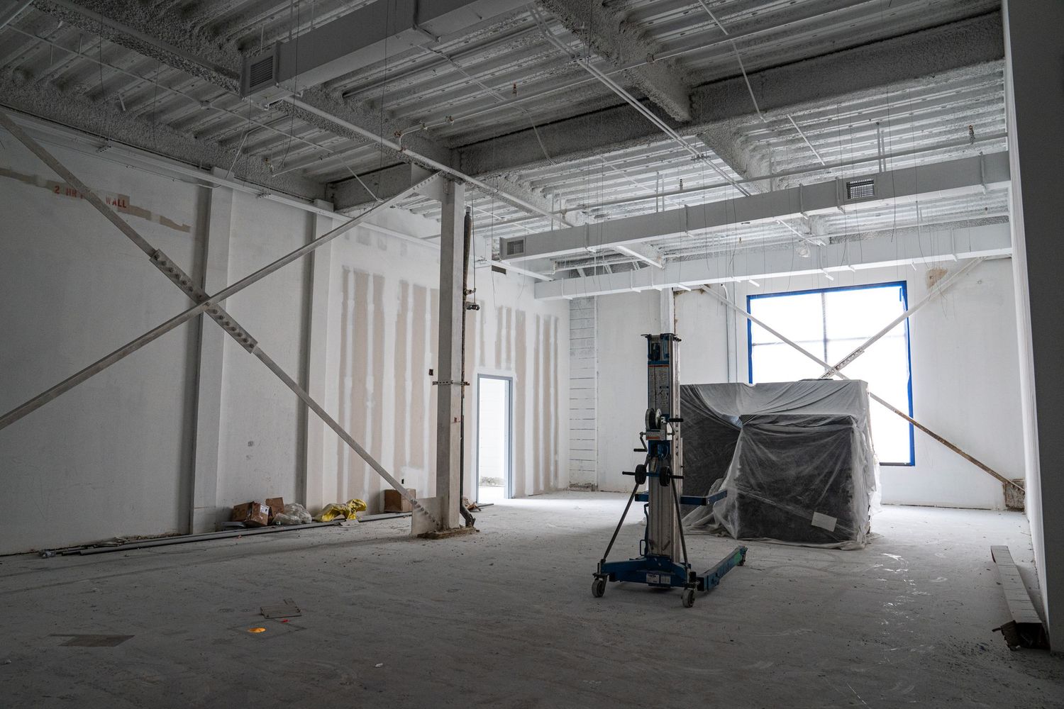 Empty warehouse space with concrete floors and industrial ceiling during construction phase.