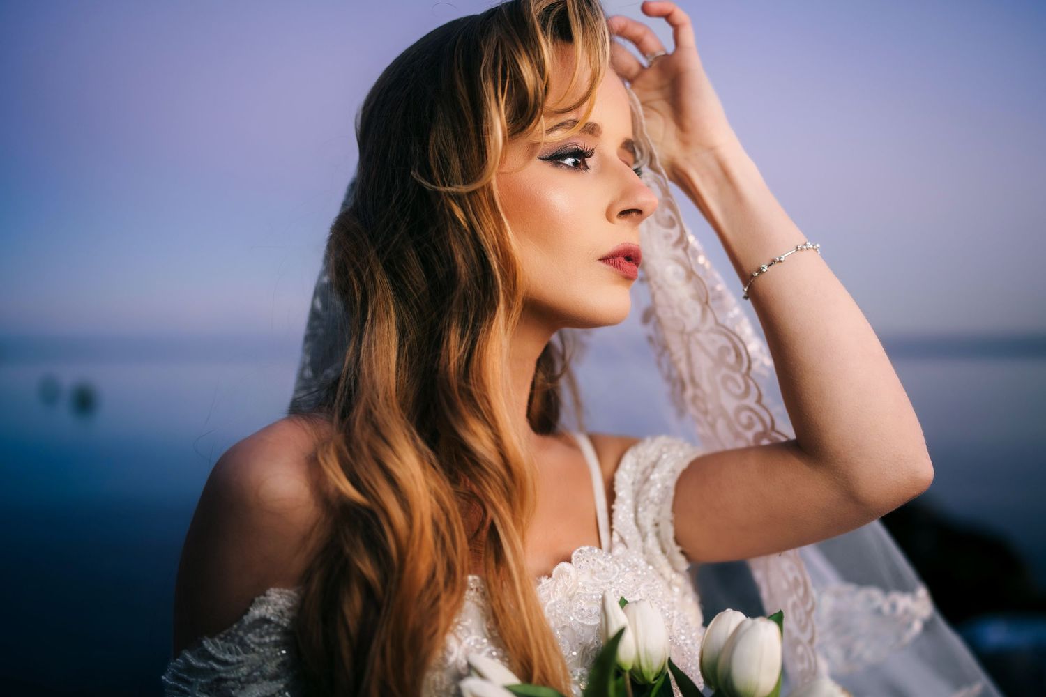 Mississauga bridal portrait. Bride in a lace wedding dress poses outdoors at sunset against a moody blue sky.