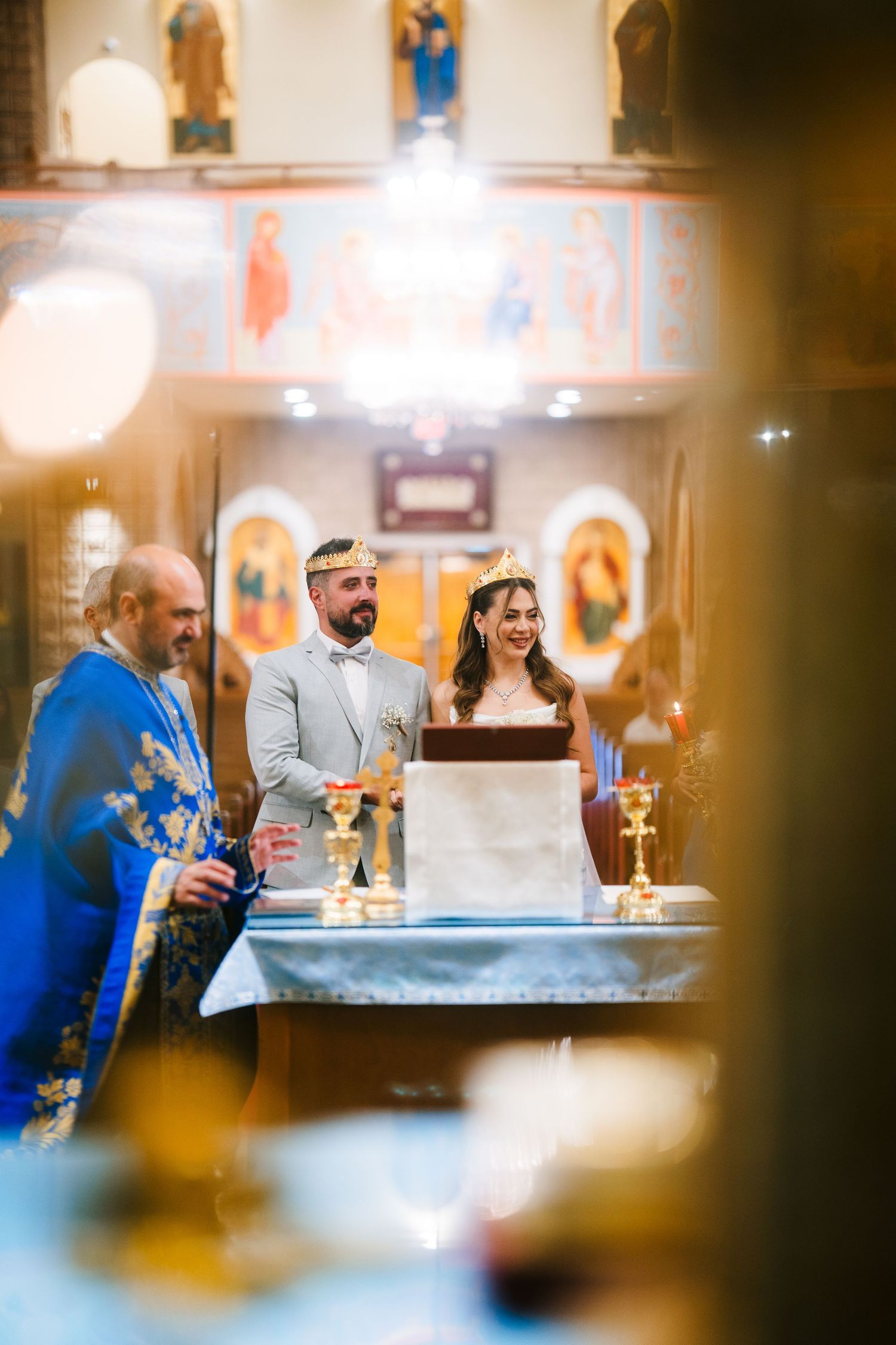 People gathered at a church reception or social event with warm lighting and religious iconography in the background.