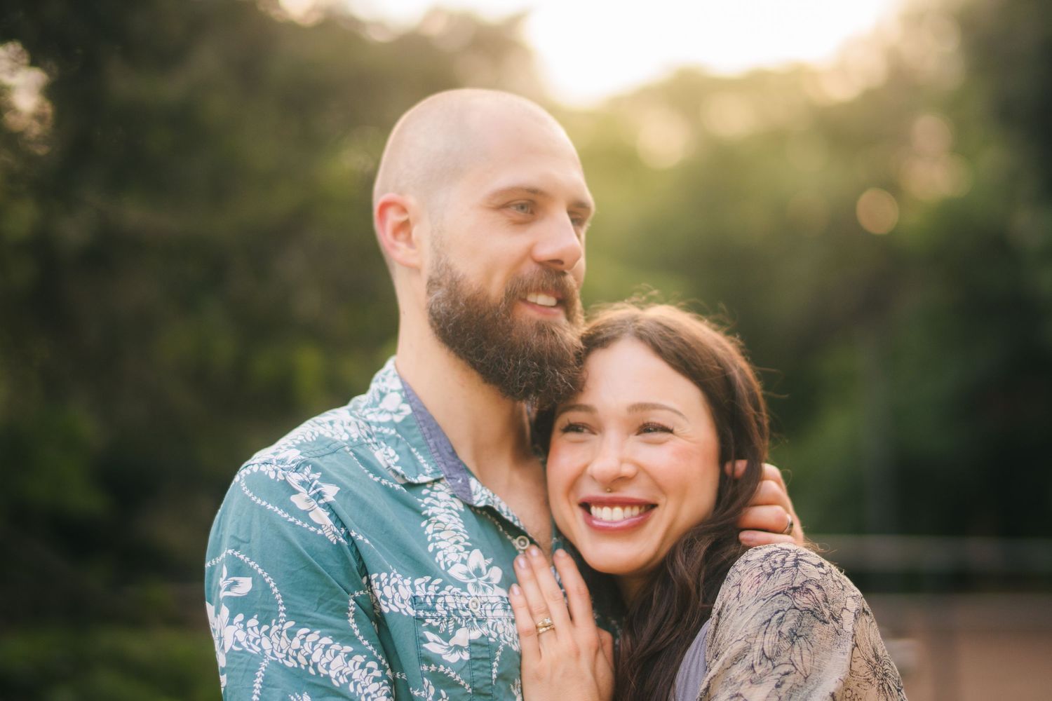 A couple in coordinated blue and white outfits share an intimate moment during a sunset photo session outdoors.