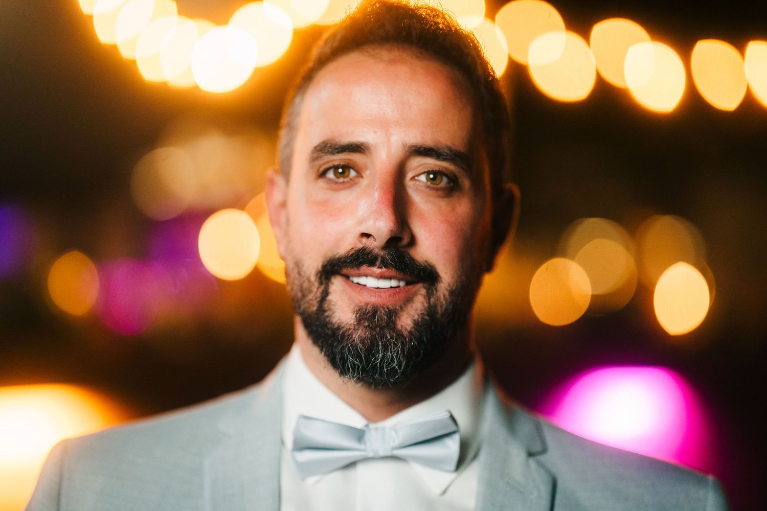 Glowing string lights create a warm bokeh effect in the background during an evening event.