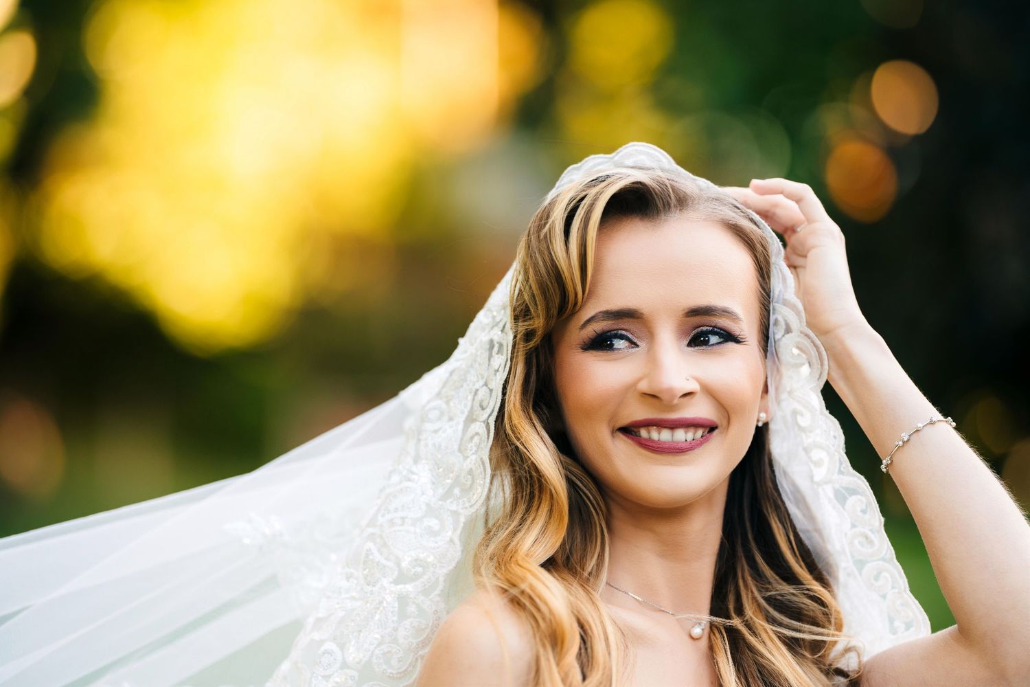 Mississauga bridal portrait. Bride in white lace wedding dress poses outdoors with natural bokeh lighting in background.