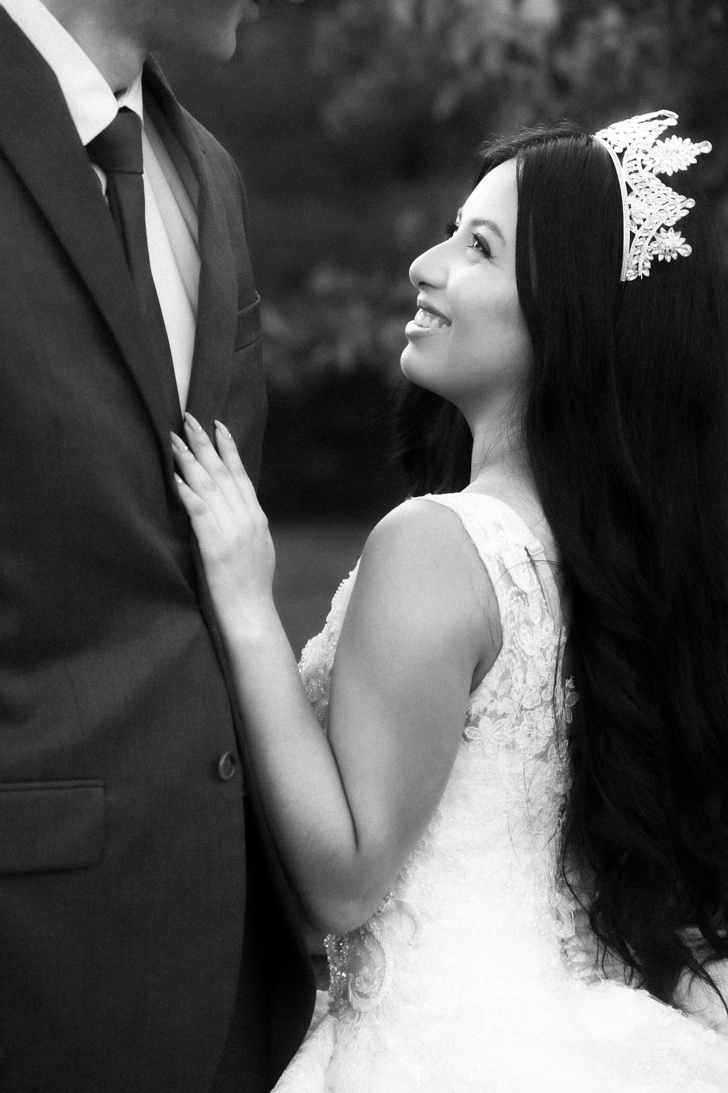 A romantic black and white wedding portrait shows a bride gazing upward while standing next to her groom.