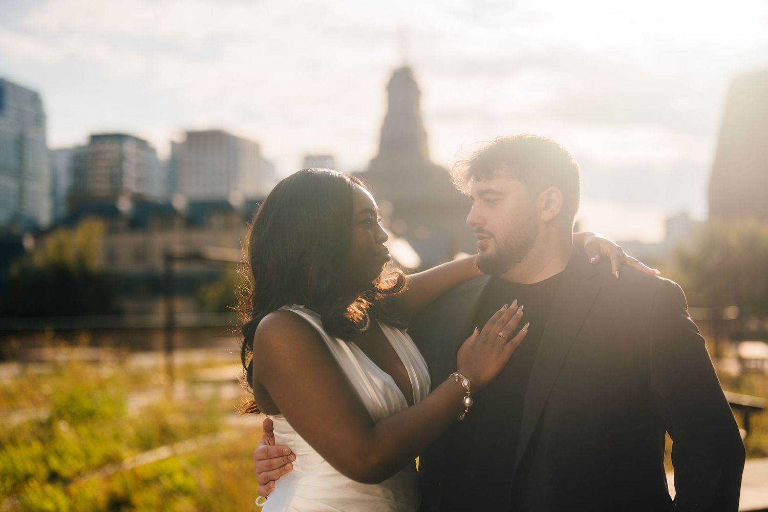 Toronto City hall weddings silhouetted couple embraces during golden hour with a cityscape in the background.