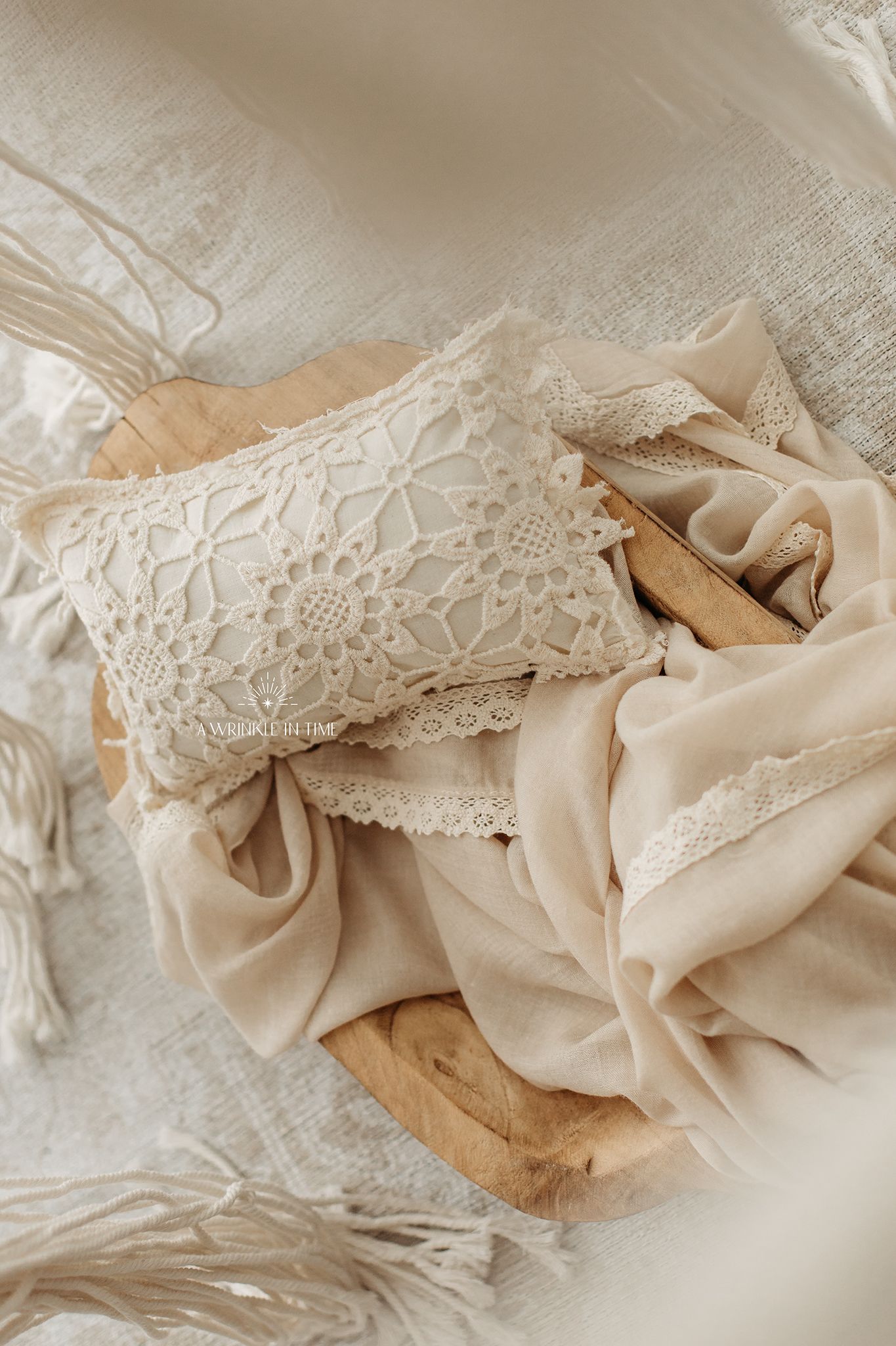 Elegant ivory lace pillow and beige chiffon fabric draped over wooden tray in soft boho aesthetic flatlay.