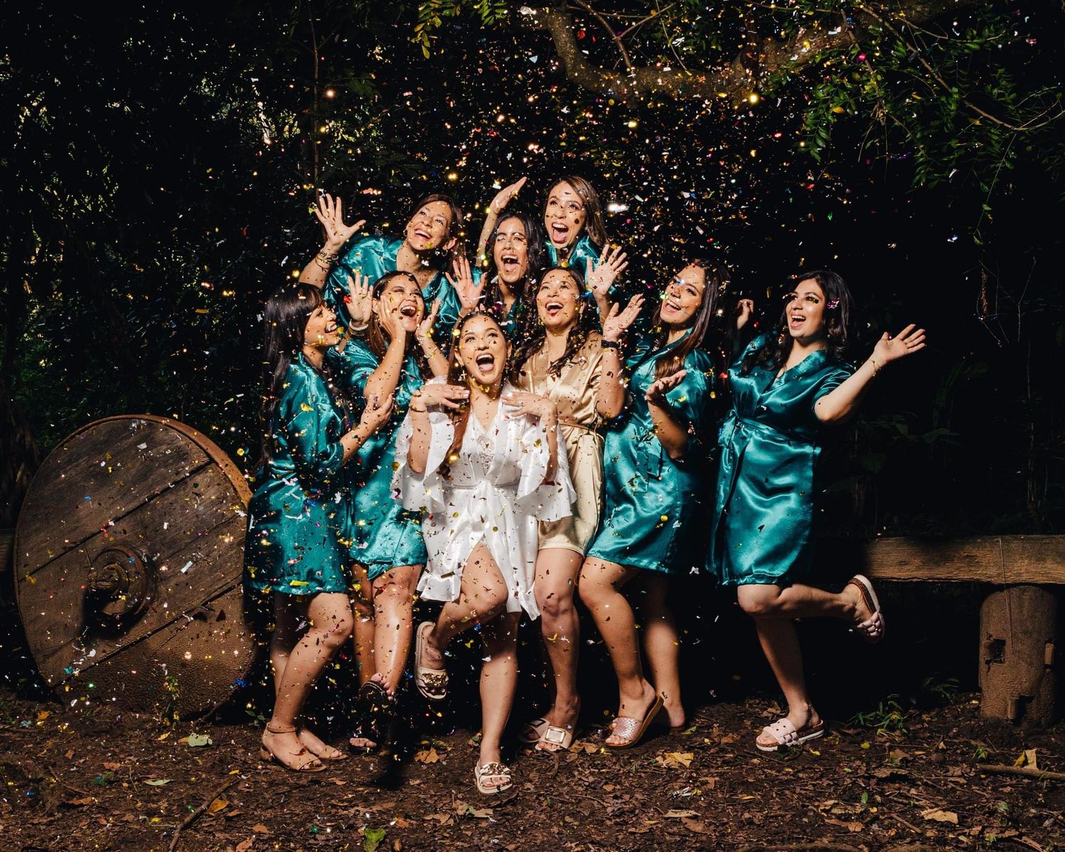Bridesmaids in turquoise dresses celebrate with confetti alongside the bride.
