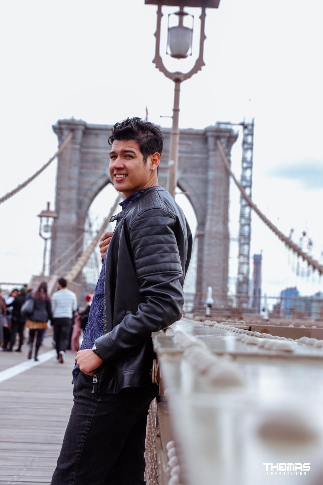 Casual portrait on Brooklyn Bridge with iconic architecture in background.