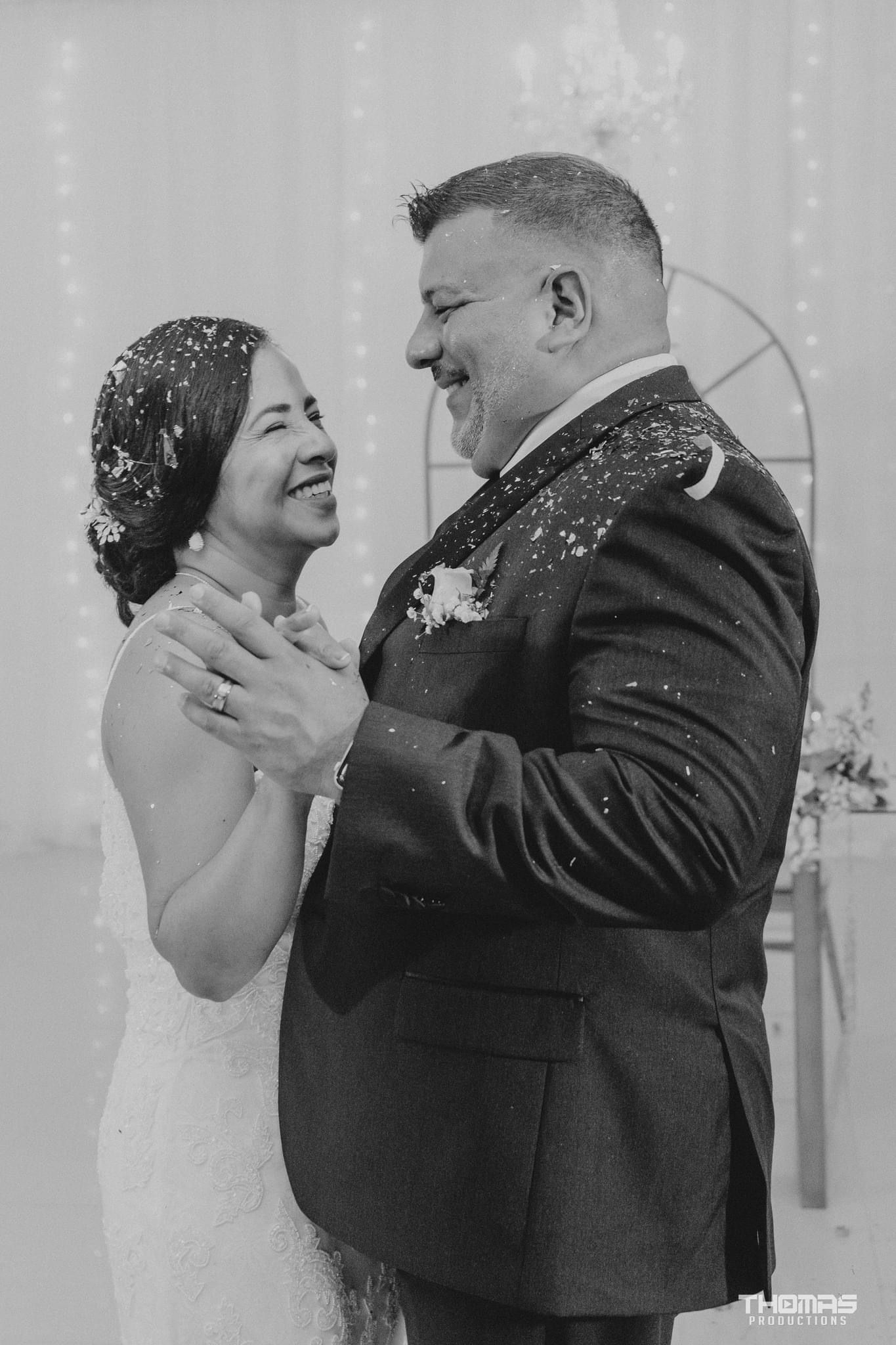 A couple shares an intimate dance moment under falling snow at their winter wedding reception.