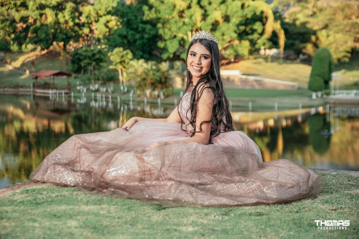 Romantic outdoor bridal portrait by a lake with flowing rose gold dress at sunset.