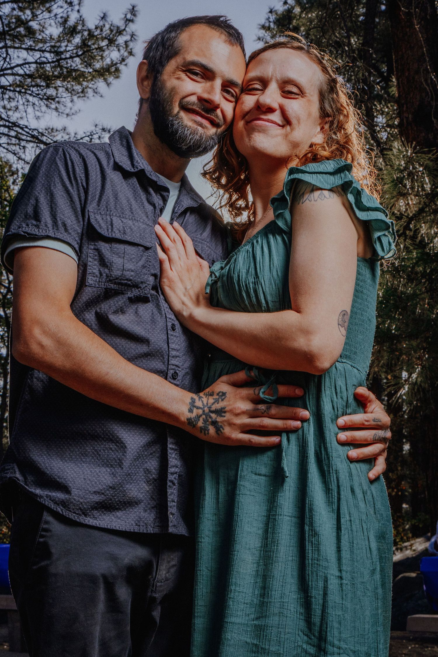 Couple sharing intimate moment in casual attire against forest setting.