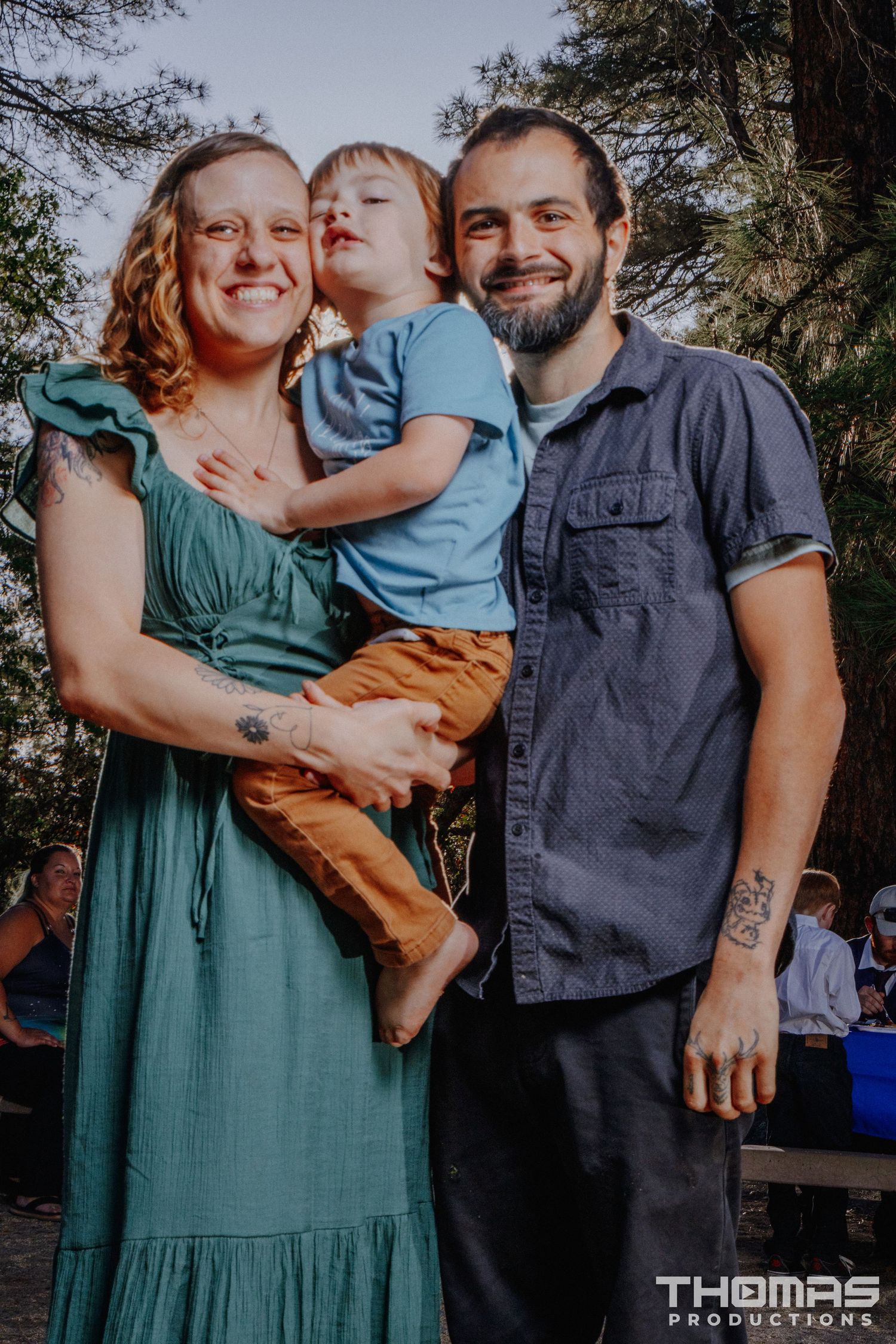 A family poses together outdoors with their young child in casual attire.