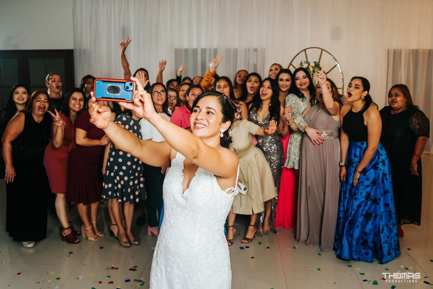 Joyful wedding reception scene with a bouquet toss moment among celebrating guests.