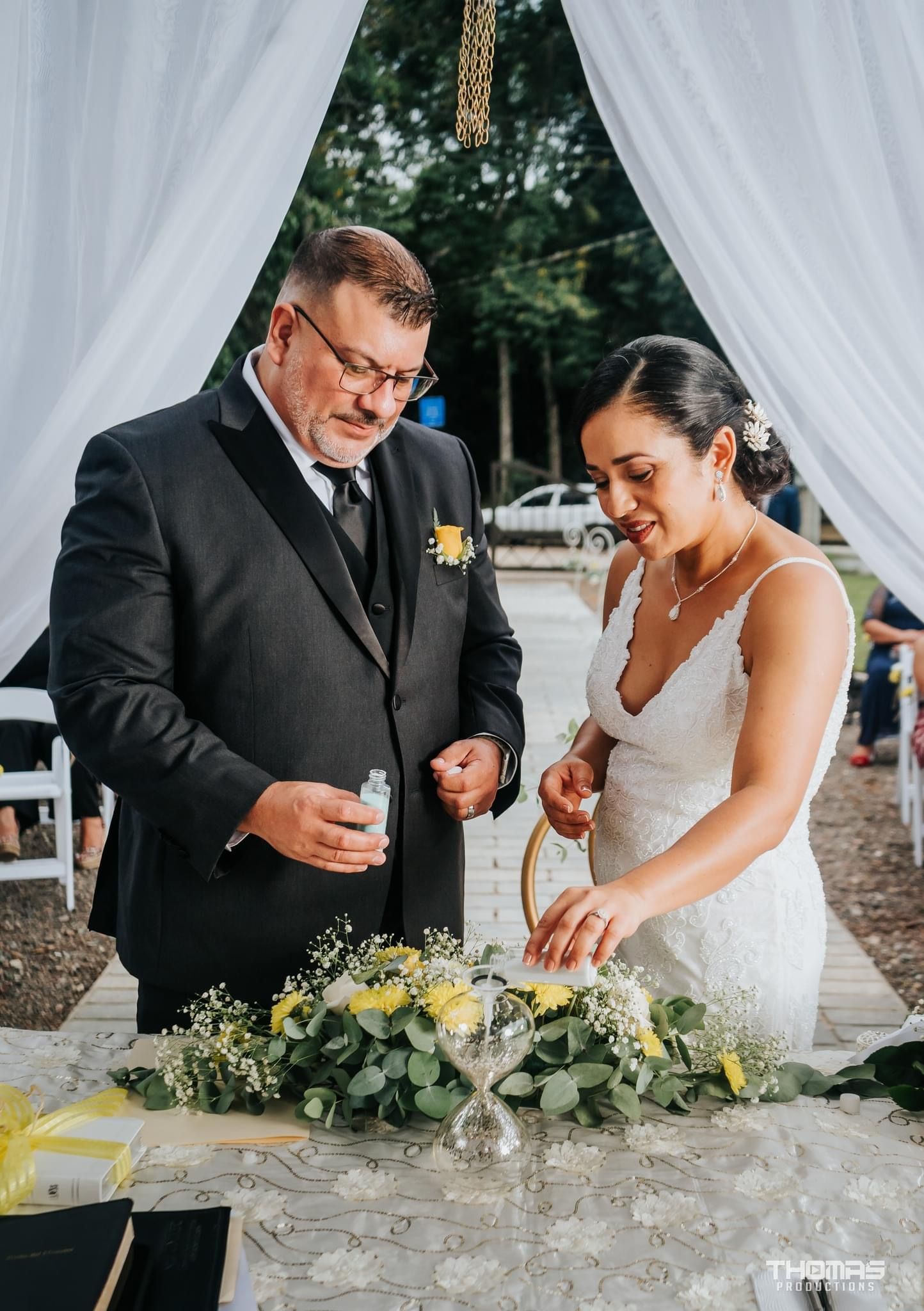 A couple signs their marriage license under an elegant white draped ceremony arch.