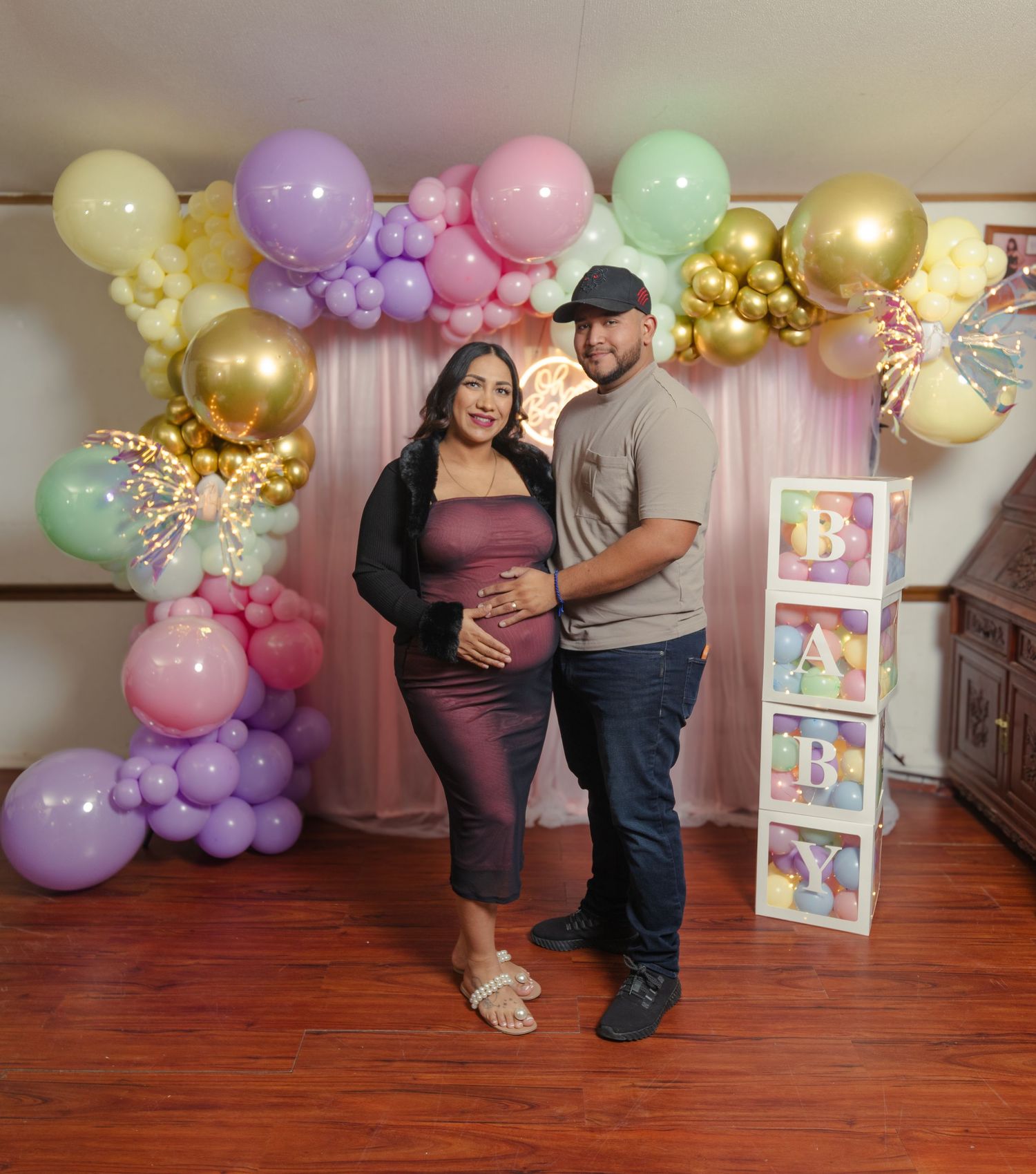 Colorful balloon arch display with pastel and gold balloons against indoor wall setting.