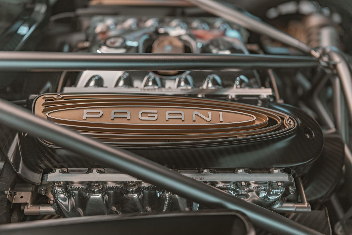 Close-up of a Pagani engine bay featuring the iconic Pagani logo on a carbon fiber engine cover.