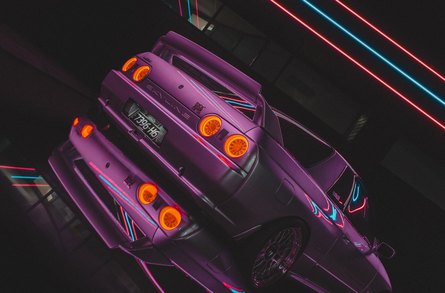 Purple Nissan Skyline GT-R rear view with glowing taillights in neon-lit darkness.