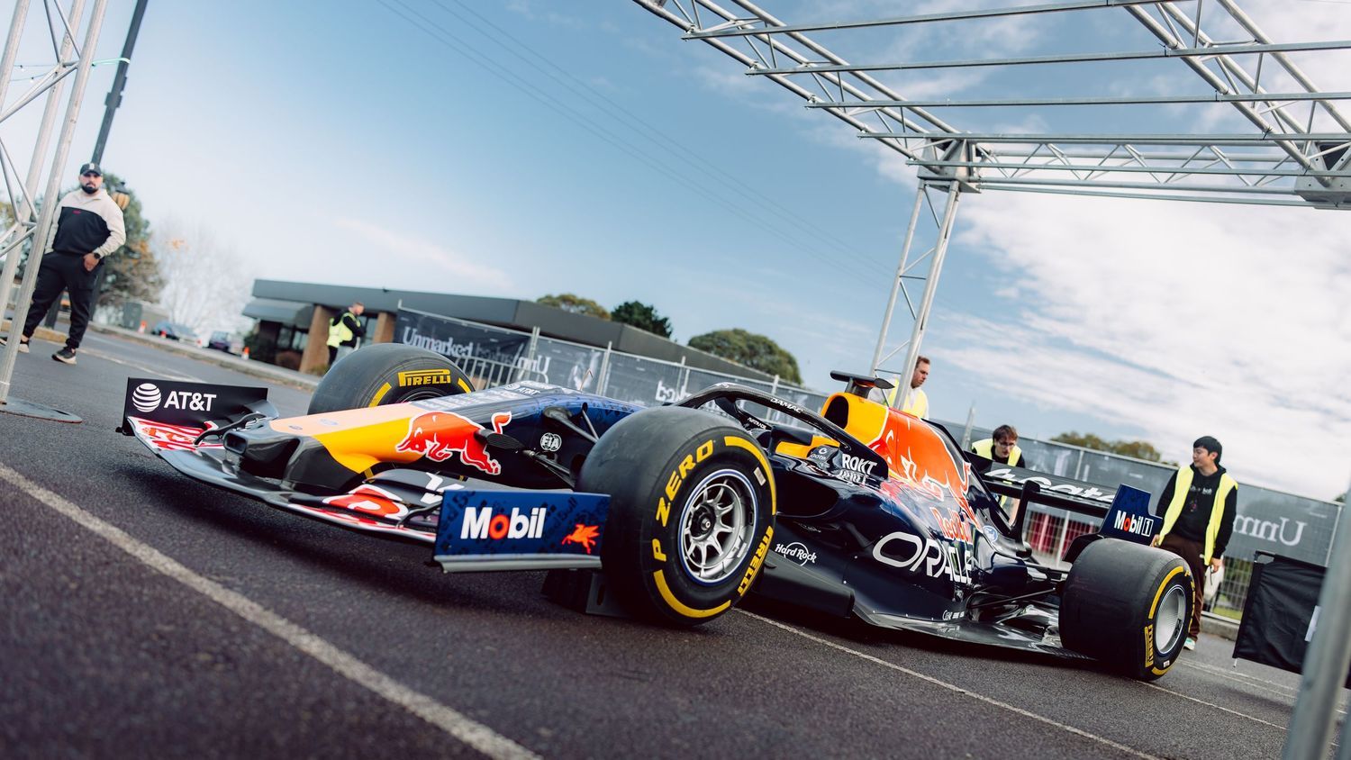 Red Bull Racing Formula 1 car on display at an outdoor event with team members and sponsor logos visible.