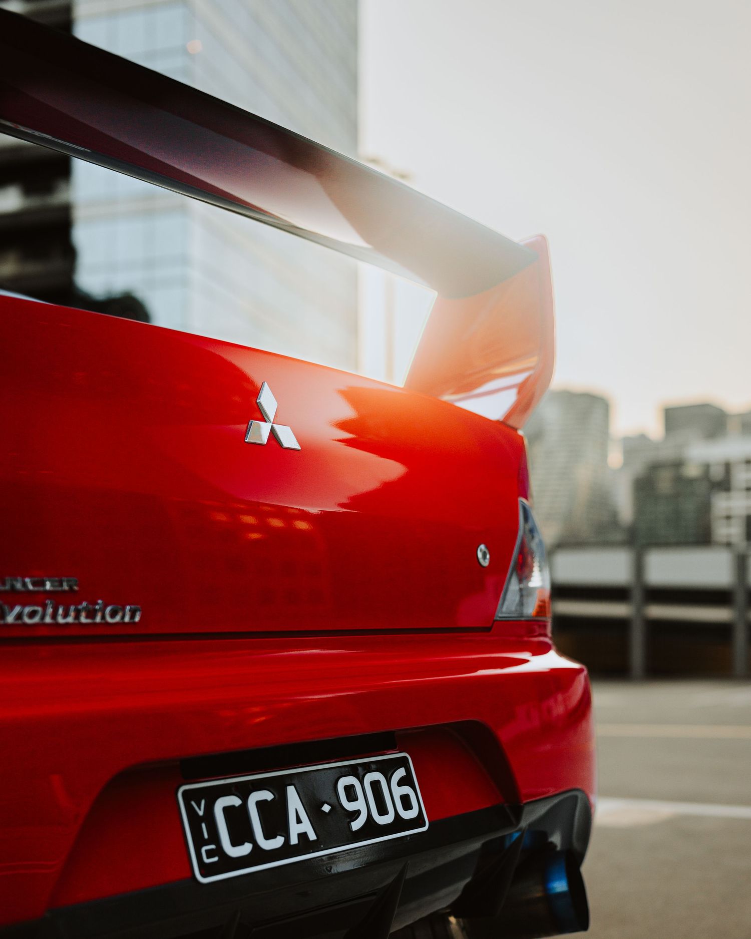 Red Mitsubishi Lancer Evolution rear spoiler and badge in an urban setting