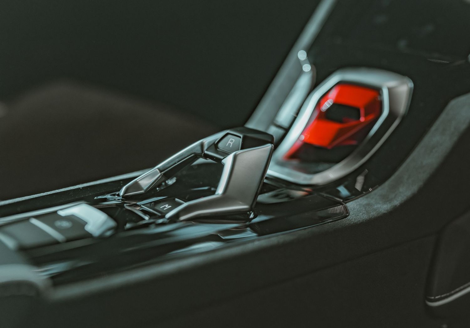 Close-up of a luxury car interior center console with a red sports car model placed near the gear shift.