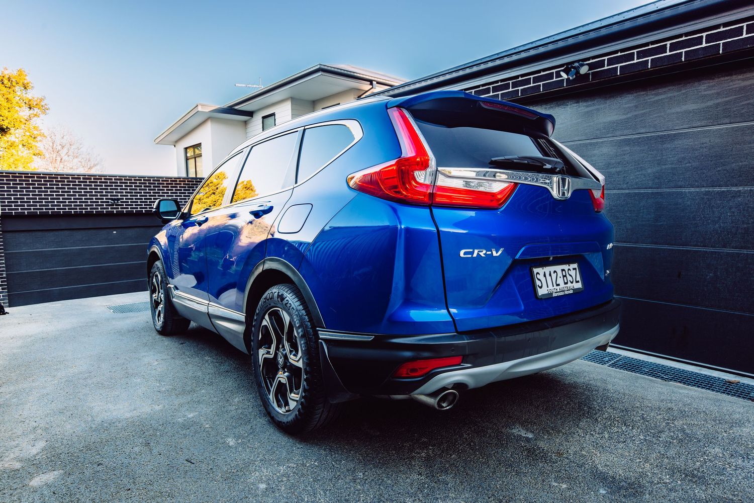 Blue Honda CR-V SUV parked in driveway, rear three-quarter view