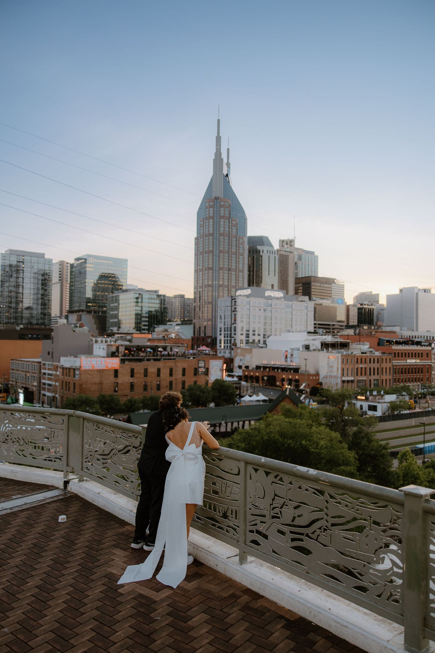 Bride and groom share a romantic moment on a rooftop overlooking the Nashville skyline at dusk.