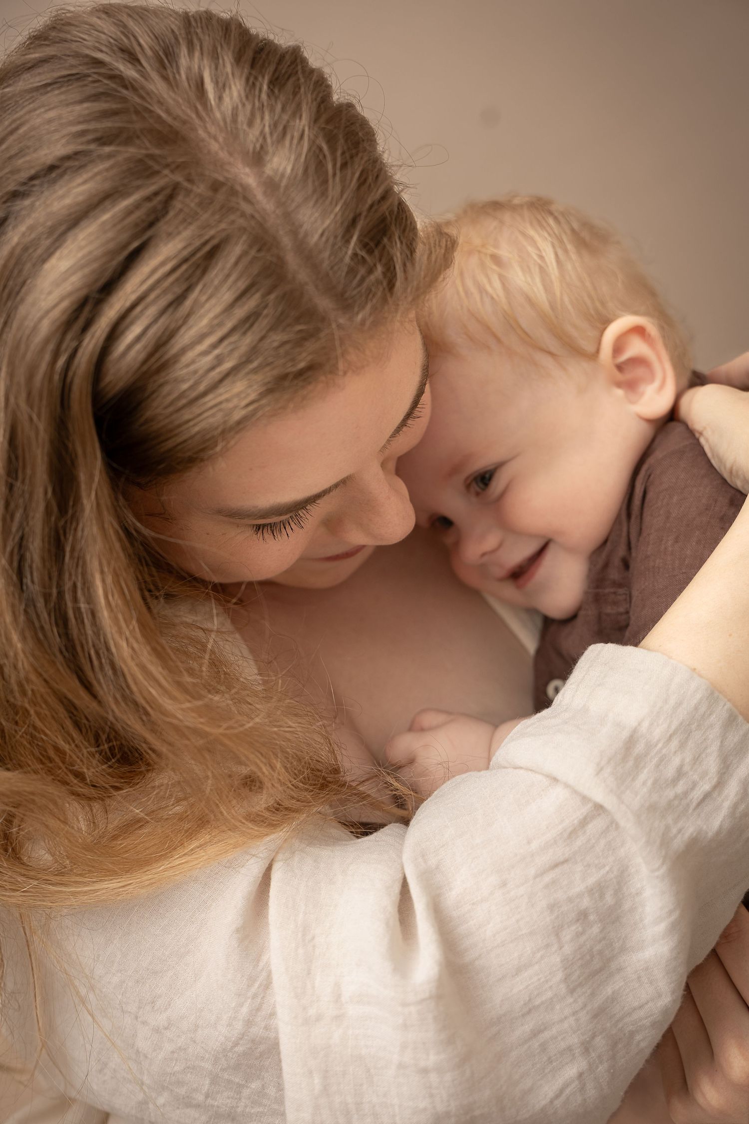 A loving mother tenderly holds her smiling baby, sharing a warm and joyful moment together.
