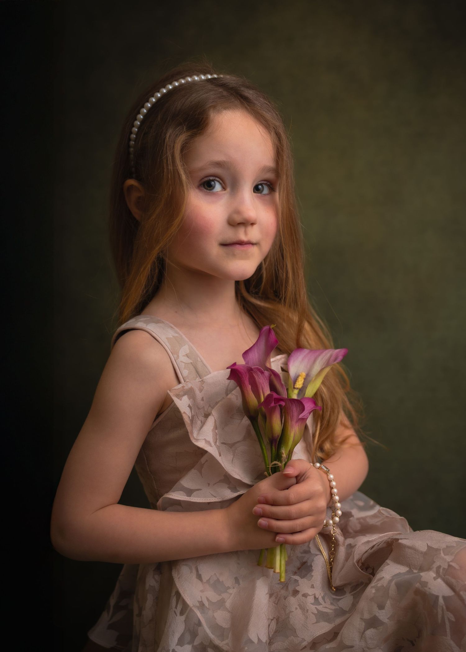 Fine-art kinderportret van een jong meisje in een beige jurk met roze calla's en een parelarmband.
