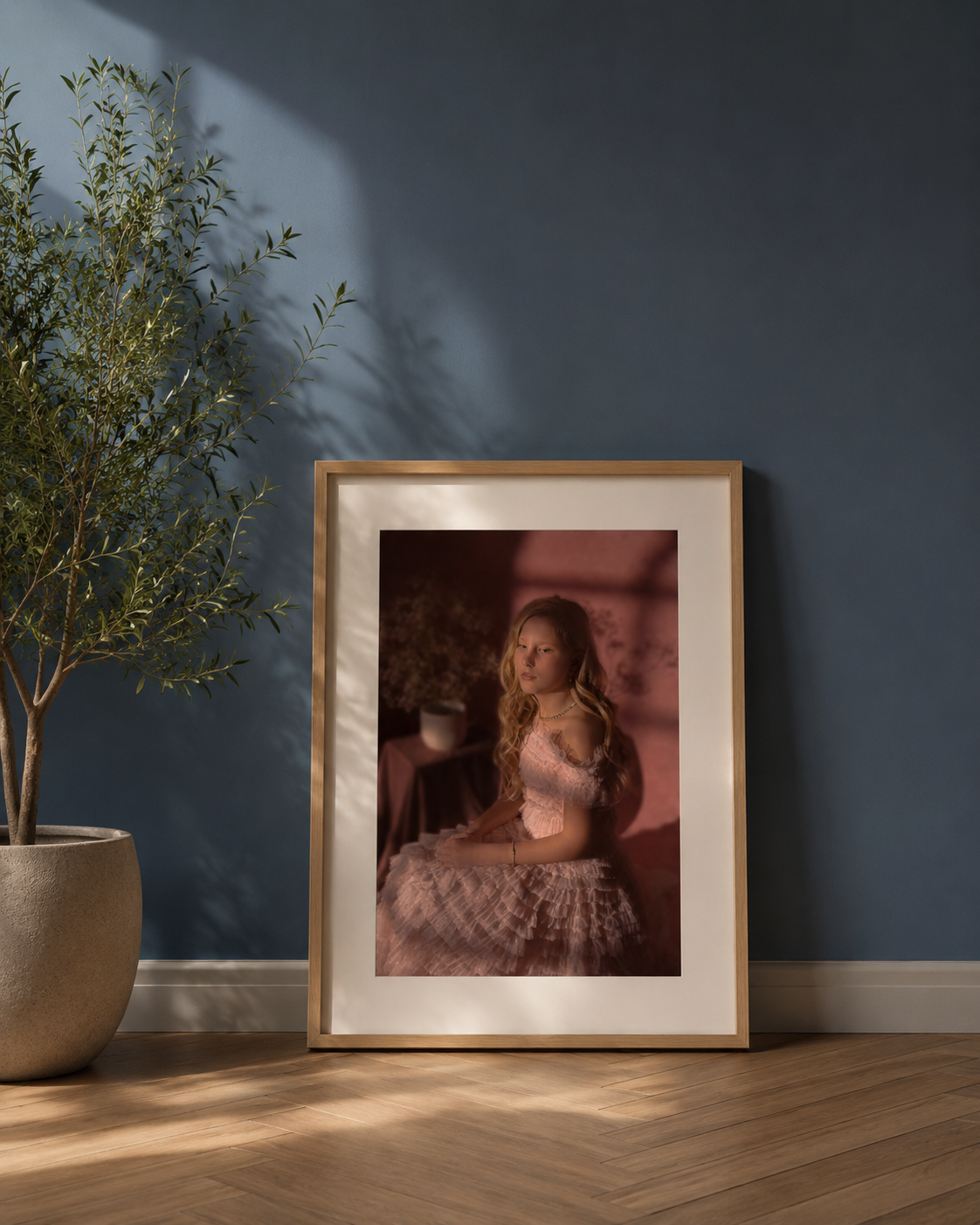 Ingelijst portret van een vrouw in roze als wanddecoratie boven een houten dressoir in een warme woonkamer.